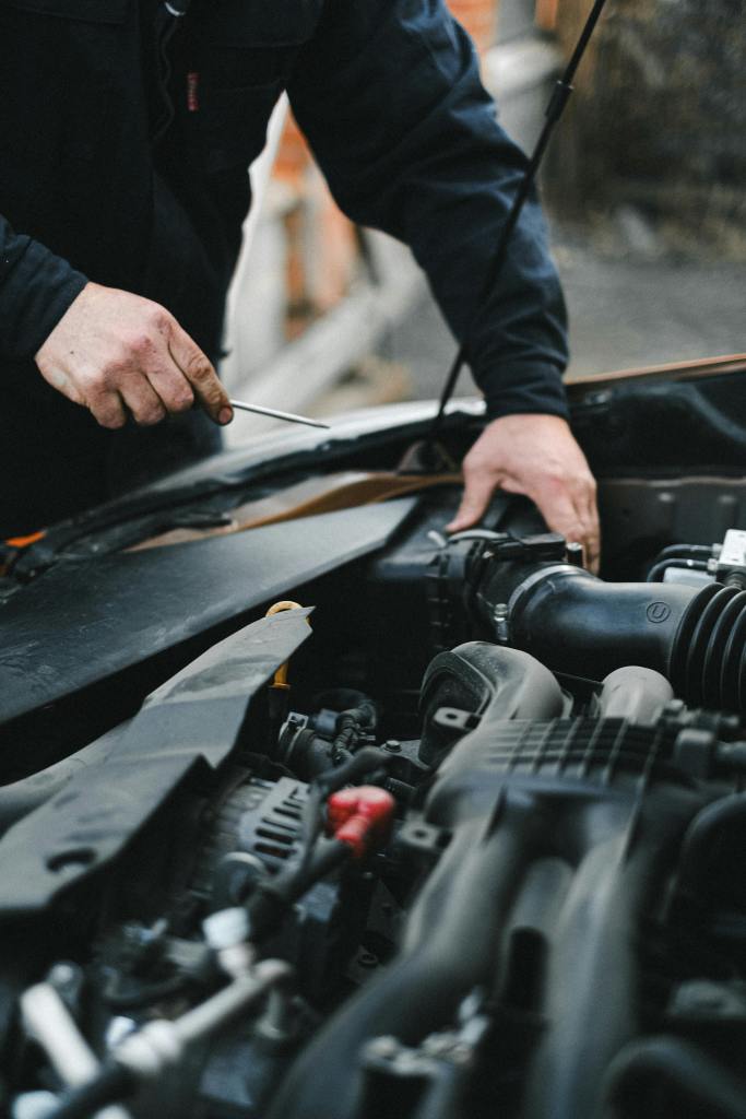 doorstep car service in Bangalore - BestFitment. A mechanic working on a car engine with tools, focused on repairs.